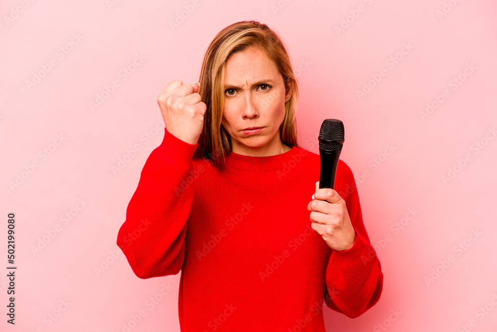 Young caucasian singer woman isolated on pink background showing fist to camera, aggressive facial expression. Young caucasian singer woman isolated on pink background showing fist to camera, aggressive facial expression.