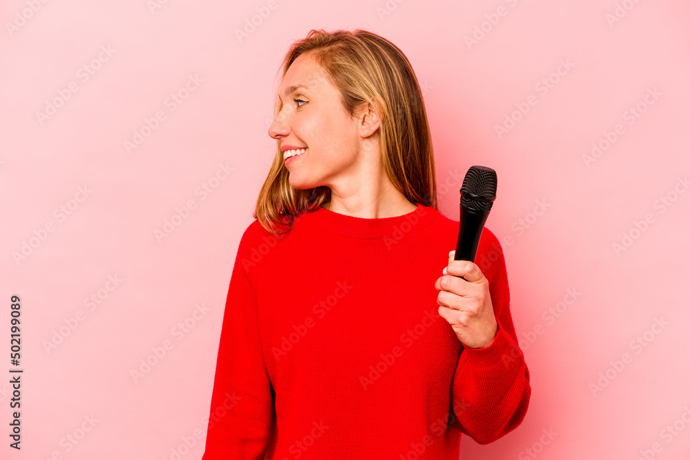 Young caucasian singer woman isolated on pink background looks aside smiling, cheerful and pleasant. Young caucasian singer woman isolated on pink background looks aside smiling, cheerful and pleasant.