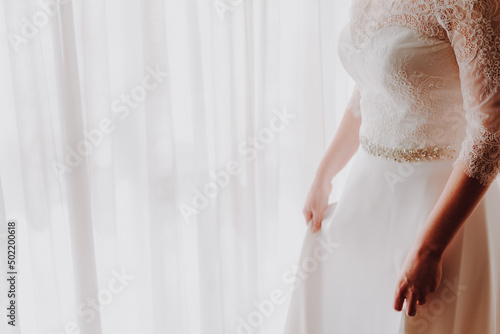 An unrecognizable bride woman in her wedding dress, with white copy space and added film grain.