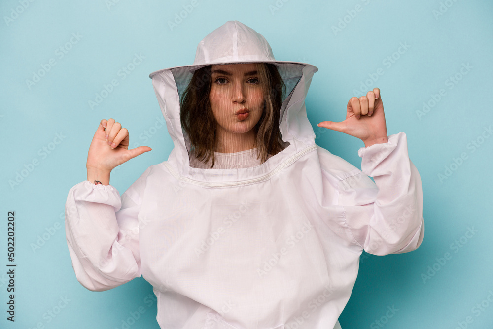 Young caucasian beekeeper woman isolated on blue background feels proud and self confident, example to follow. Young caucasian beekeeper woman isolated on blue background feels proud and self confident, example to follow.