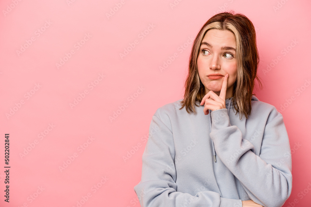 Young caucasian woman isolated on pink background looking sideways with doubtful and skeptical expression. Young caucasian woman isolated on pink background looking sideways with doubtful and skeptical expression.