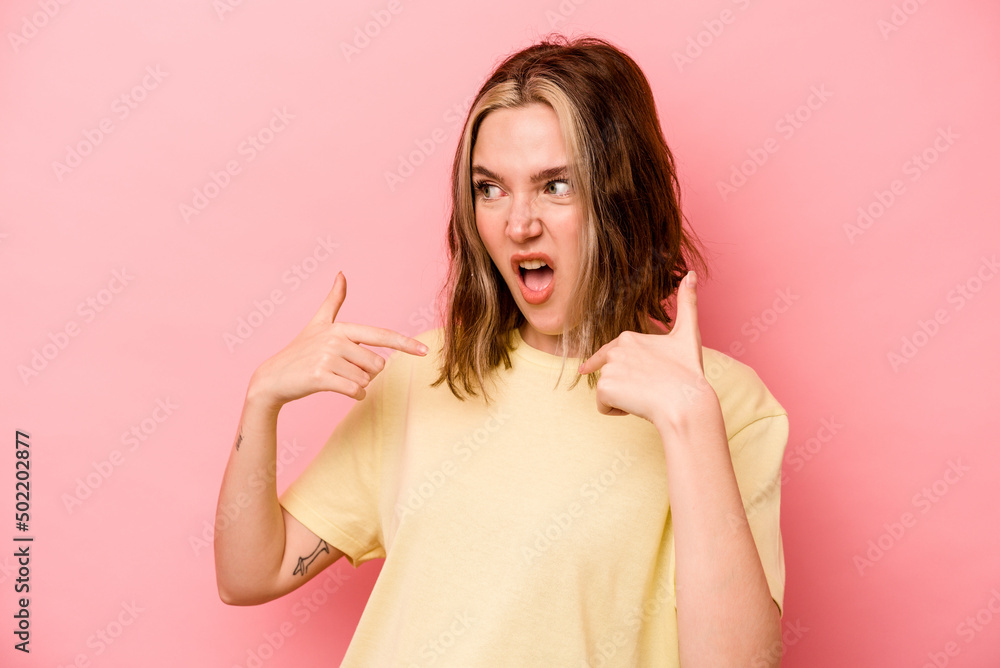 Young caucasian woman isolated on pink background surprised pointing with finger, smiling broadly. Young caucasian woman isolated on pink background surprised pointing with finger, smiling broadly.
