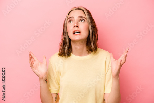 Young caucasian woman isolated on pink background screaming to the sky, looking up, frustrated. photo