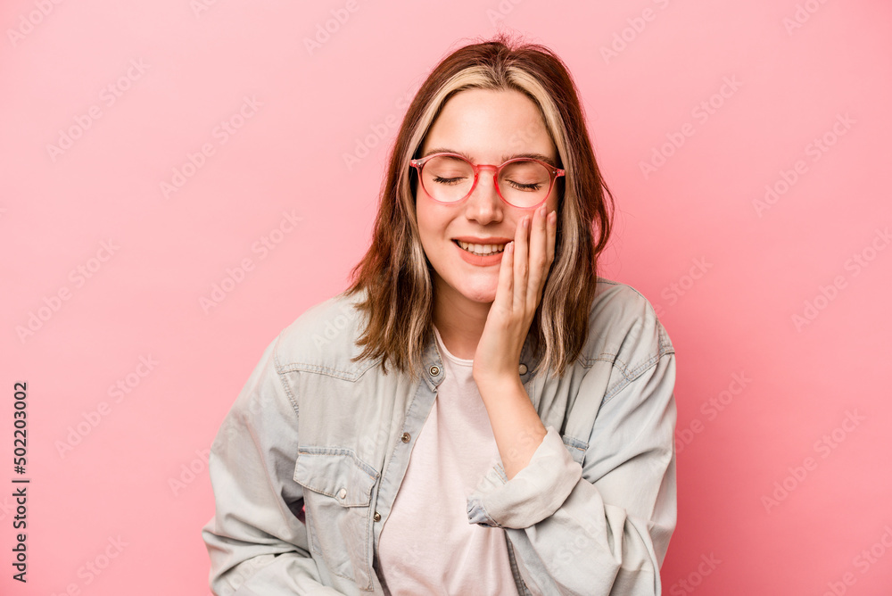 Young caucasian woman isolated on pink background laughs happily and has fun keeping hands on stomach.