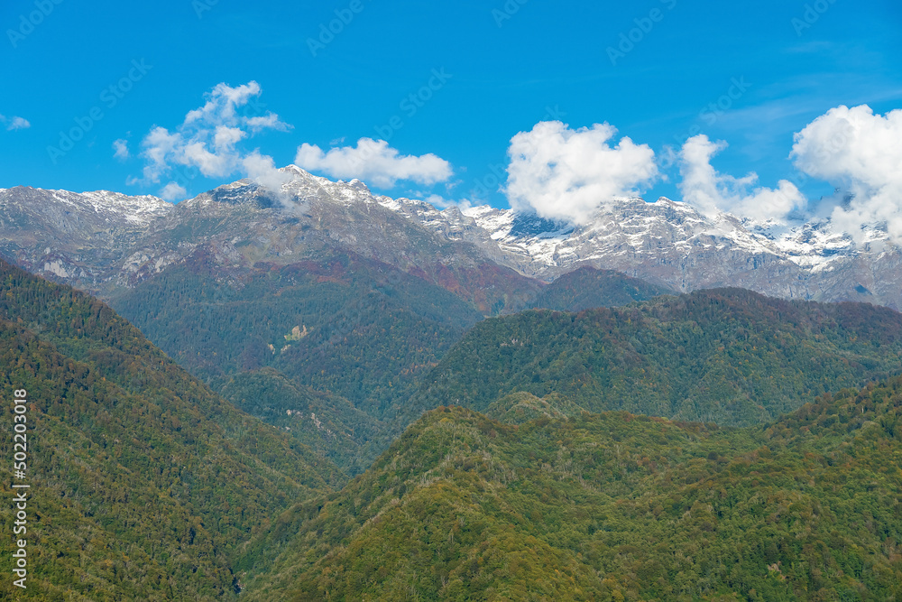 Beautiful green mountains with snowy peaks on a sunny day. Beautiful mountain landscape