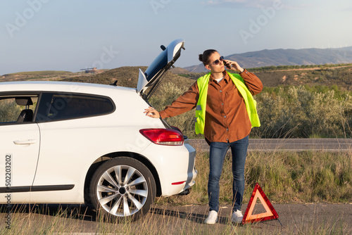 Young handsome modern and hipser man leaning on his white car after a breakdown in the middle of the road photo