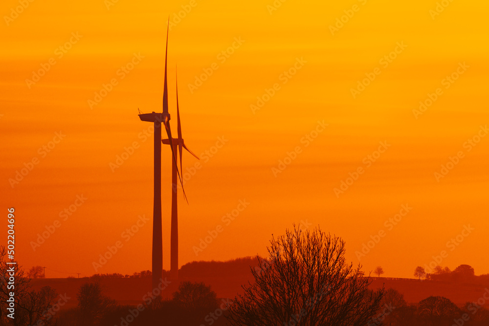 Obraz premium Silhouette of wind turbines at sunrise