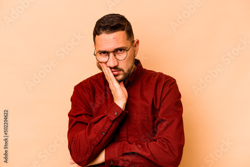 Young hispanic man isolated on beige background who is bored, fatigued and need a relax day.