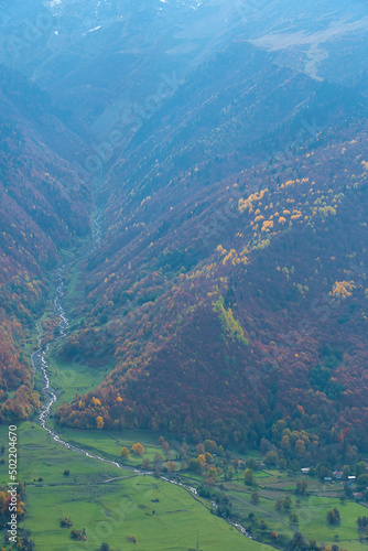 River flowing down from the mountain along the village at the foot of the greatest Caucasus mountains on an autumn day. Beautiful landscape of autumn mountains. Vertical photo © yaroslav1986
