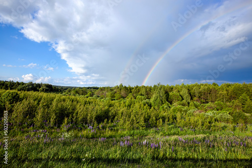 two rainbows in cloudy weather against a gray sky with clouds