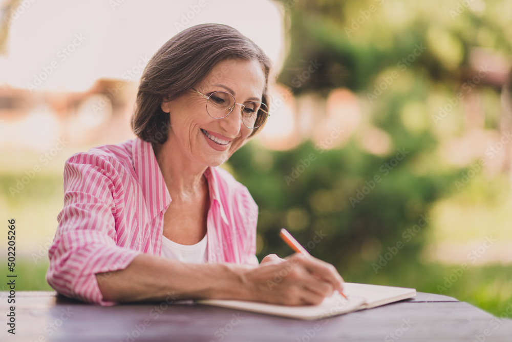 Portrait of positive satisfied person hold pen write take notes diary copybook free time outdoors Portrait of positive satisfied person hold pen write take notes diary copybook free time outdoors
