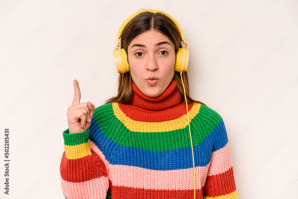 Fototapeta premium Young caucasian woman listening to music isolated on white background having some great idea, concept of creativity.
