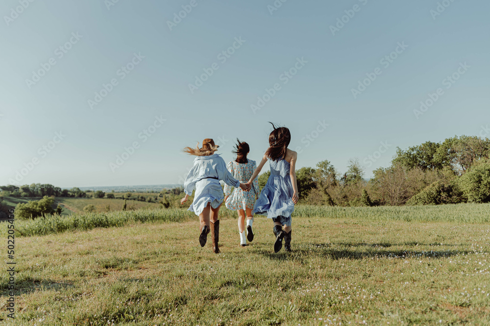 Three young girls embracing outdoors in the countryside. Three young girls embracing outdoors in the countryside.
