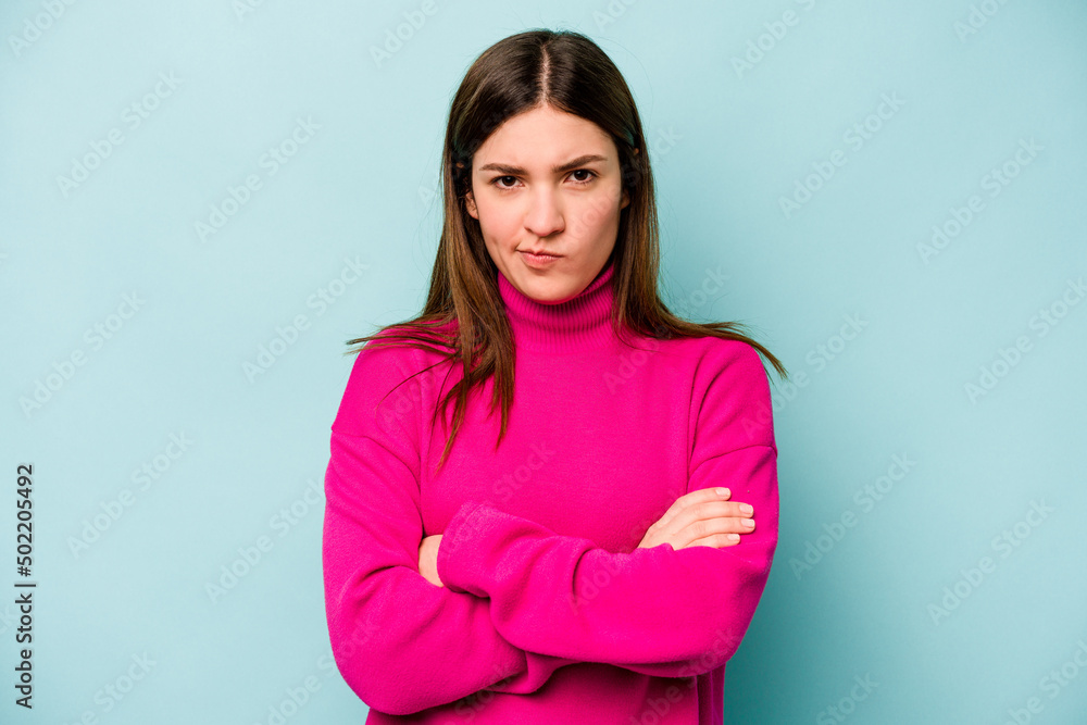 Young caucasian woman isolated on blue background frowning face in displeasure, keeps arms folded. Young caucasian woman isolated on blue background frowning face in displeasure, keeps arms folded.