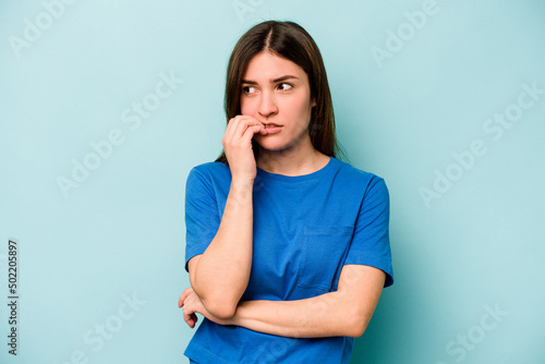 Young caucasian woman isolated on blue background biting fingernails  nervous and very anxious.