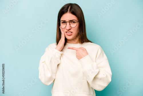 Young caucasian woman isolated on blue background having a strong teeth pain, molar ache.