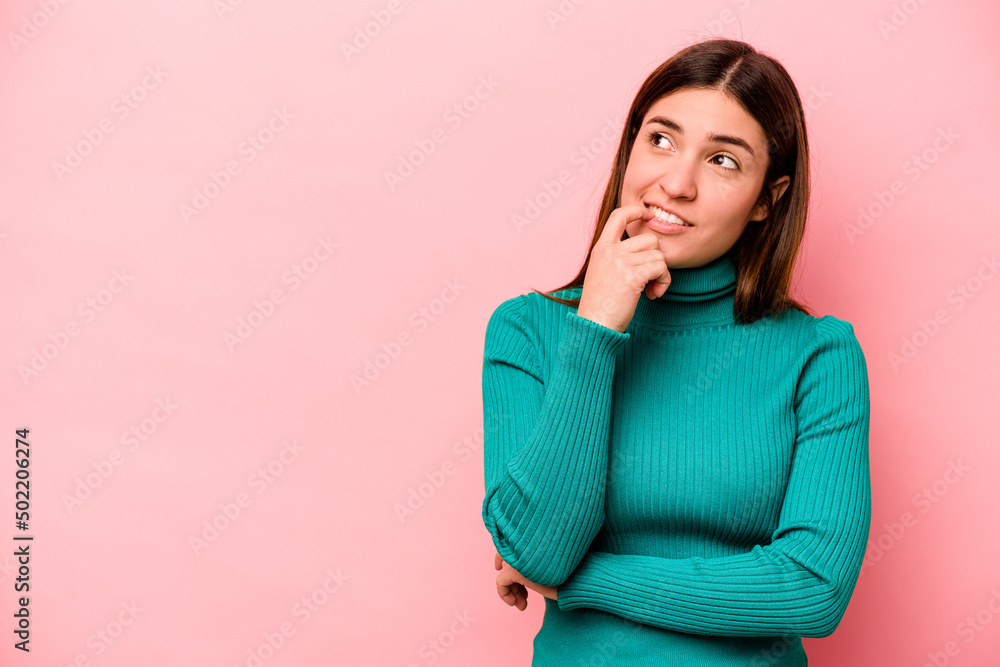 Young caucasian woman isolated on pink background relaxed thinking about something looking at a copy space. Young caucasian woman isolated on pink background relaxed thinking about something looking at a copy space.