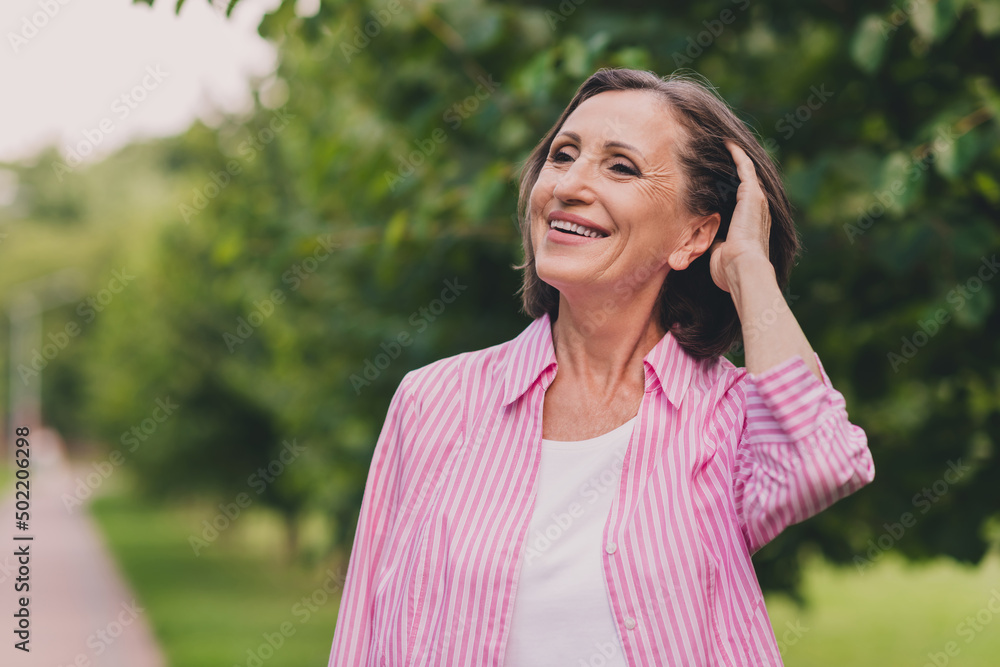 Photo of dreamy sweet retired woman dressed striped shirt enjoying good weather arm head outside countryside landscape