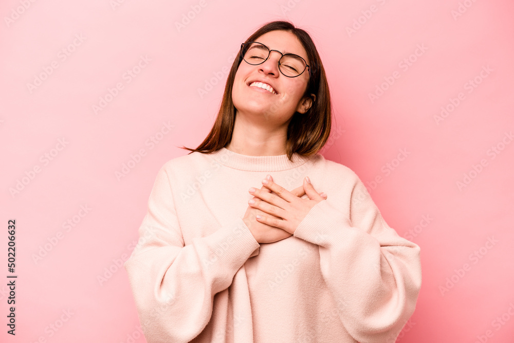 Young caucasian woman isolated on pink background laughing keeping hands on heart, concept of happiness. Young caucasian woman isolated on pink background laughing keeping hands on heart, concept of happiness.
