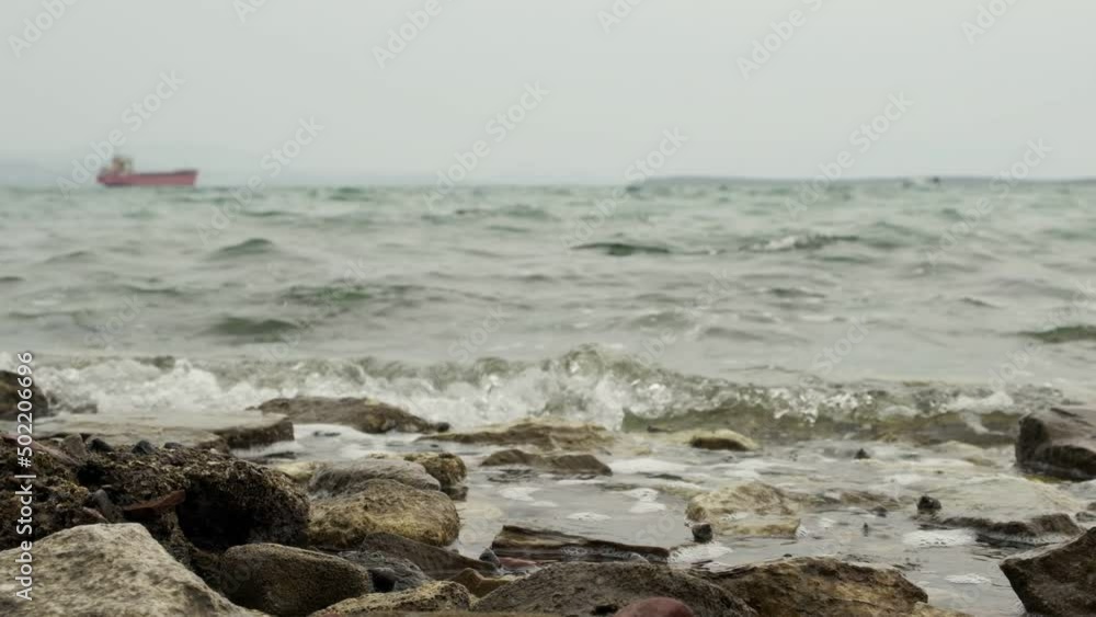 Slow motion view of rock in focus with a ship sailing in the horizon Slow motion view of rock in focus with a ship sailing in the horizon