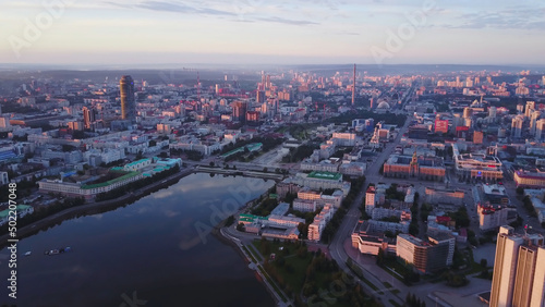Beautiful panorama of modern city with reflection of sky in river at sunset. Stock footage. Modern city was painted pink by setting sun. High-rises reflect setting sun on background of pink city