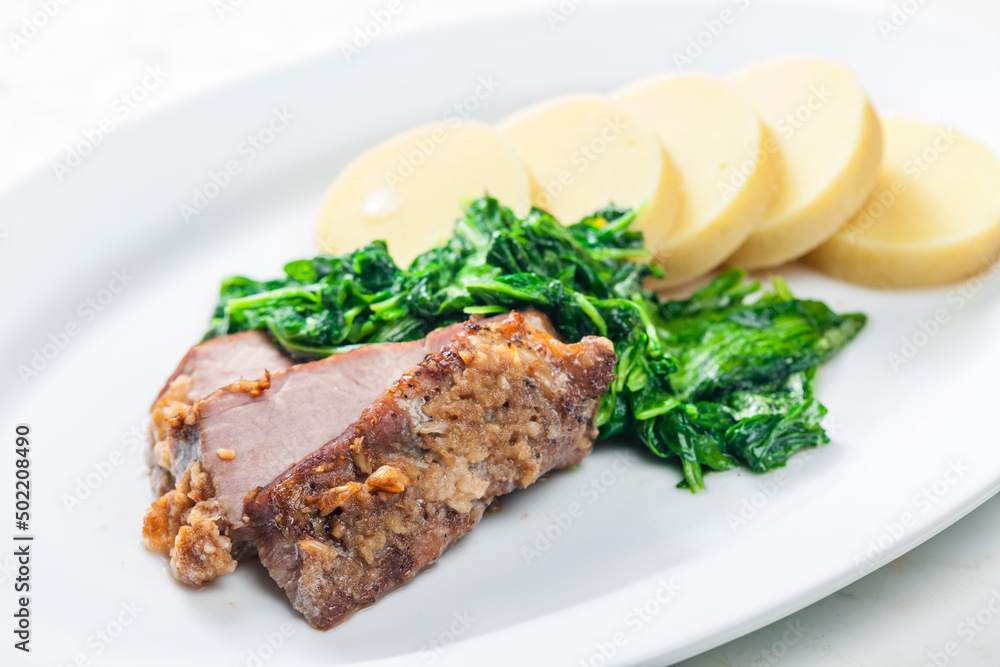 pork meat with garlic served with spinach and potato dumplings pork meat with garlic served with spinach and potato dumplings