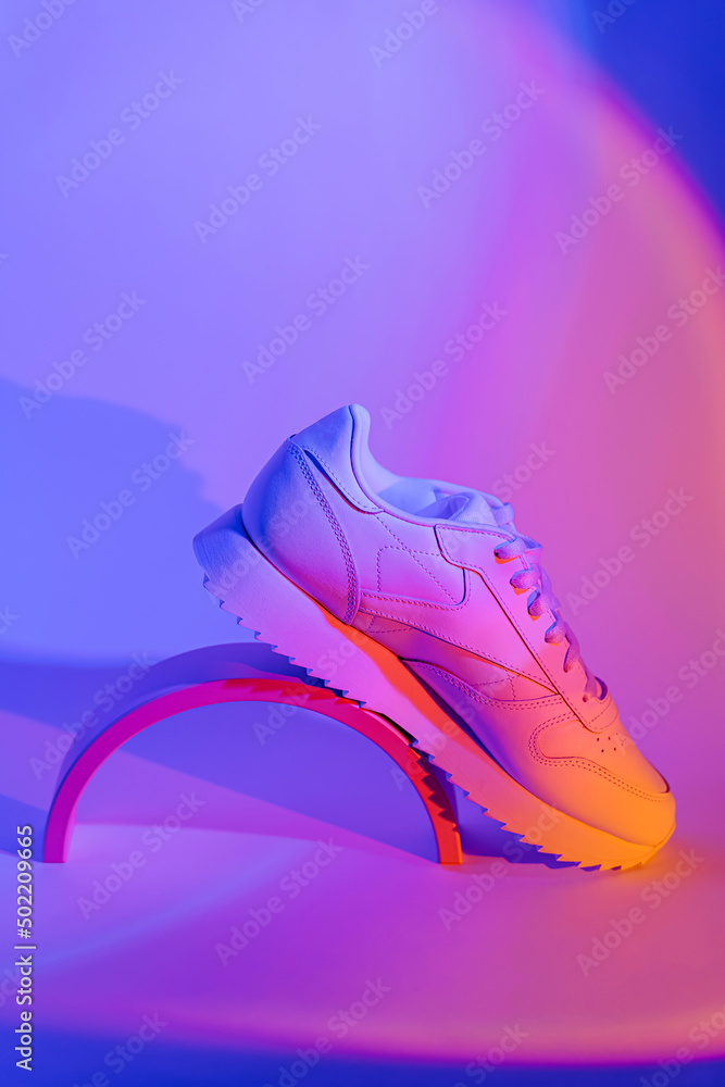 Fashion sneakers on vivid abstract background. Sport shoes in neon