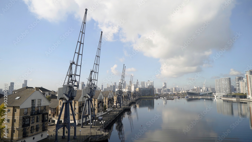 Panorama of port canal with embankment and docks. Action. Beautiful harbour canal with docks on background of European city and blue sky