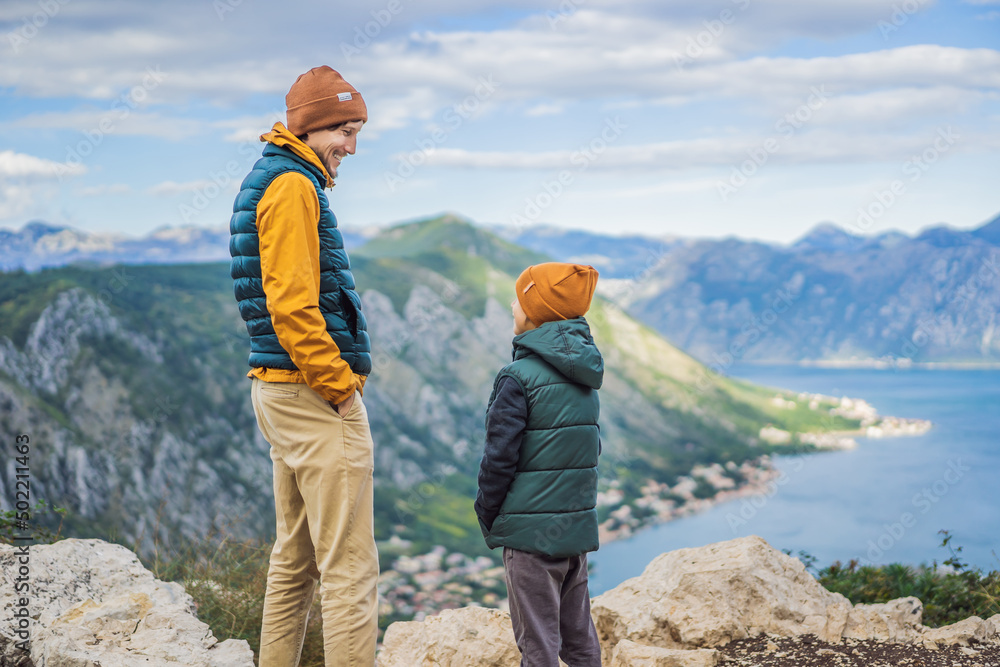 Dad and son travellers enjoys the view of Kotor. Montenegro. Bay of Kotor, Gulf of Kotor, Boka Kotorska and walled old city. Travel with kids to Montenegro concept. Fortifications of Kotor is on