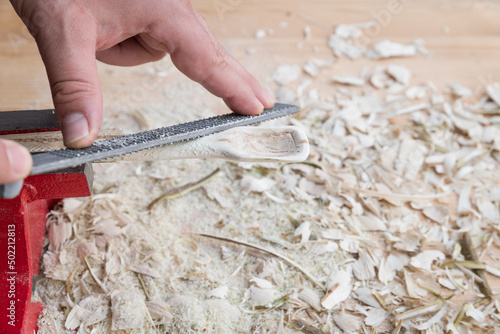 Selbst geschnitzter Holzlöffel eingespannt im Schraubstock bearbeitet mit Holzraspel Raspel auf einer Werkbank mit Holzspäne, Deutschland