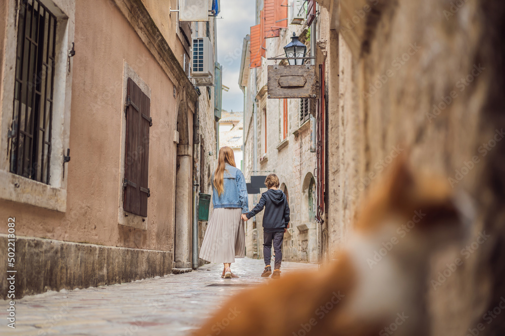 Mom and son travelers enjoying Colorful street in Old town of Kotor on a sunny day, Montenegro. Travel to Montenegro concept Mom and son travelers enjoying Colorful street in Old town of Kotor on a sunny day, Montenegro. Travel to Montenegro concept