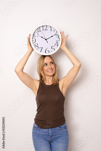 Young woman holding big clock standing isolated over white background.