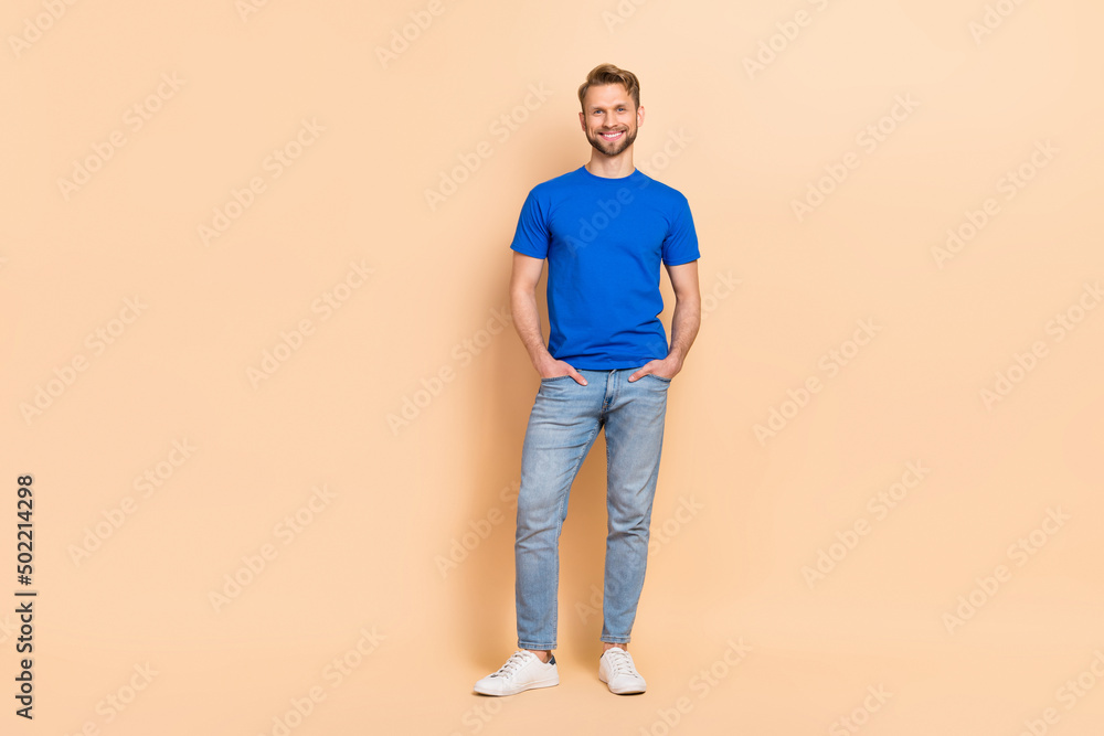 Full size photo of young cheerful man smart arms in pocket wear modern outfit isolated over beige color background Full size photo of young cheerful man smart arms in pocket wear modern outfit isolated over beige color background