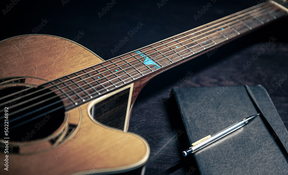 Fototapeta premium Close-up, acoustic guitar and notepad on a dark background.