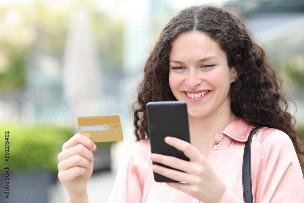 Happy woman buying on line with credit card and cell phone