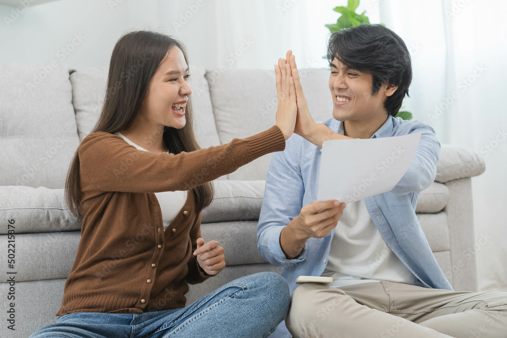 Happy excited, smiling asian young couple love, wife and husband hold paper letter, reading paperwork document getting, receive job promotion, tax refund or loan mortgage approval, good news by mail. Happy excited, smiling asian young couple love, wife and husband hold paper letter, reading paperwork document getting, receive job promotion, tax refund or loan mortgage approval, good news by mail.