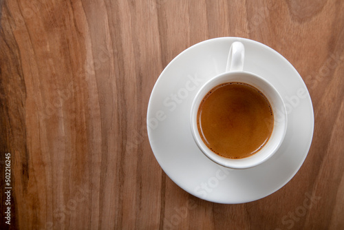 White cup of espresso on wooden background top view