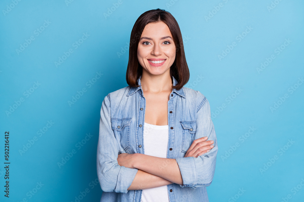 Photo of sweet confident woman wear jeans shirt smiling arms crossed isolated blue color background Photo of sweet confident woman wear jeans shirt smiling arms crossed isolated blue color background