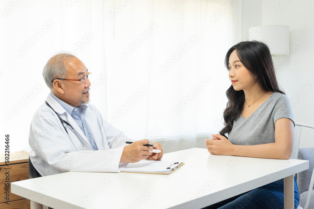 Old doctor in professional uniform examining young patient woman at hospital or medical clinic. Health care , medical and doctor staff service concept. Old doctor in professional uniform examining young patient woman at hospital or medical clinic. Health care , medical and doctor staff service concept.