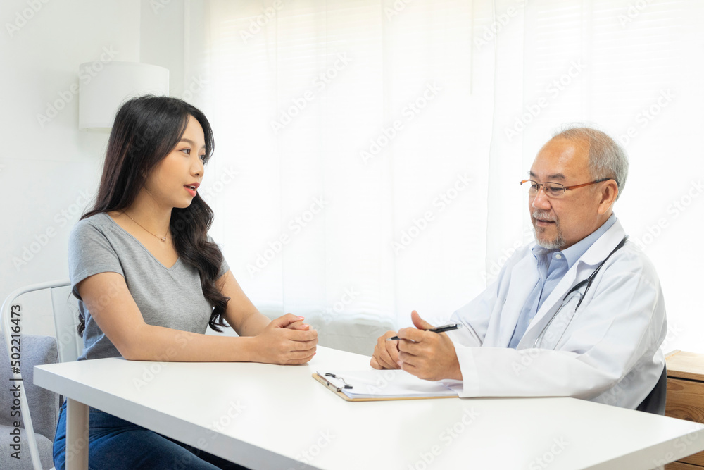 Old doctor in professional uniform examining young patient woman at hospital or medical clinic. Health care , medical and doctor staff service concept. Old doctor in professional uniform examining young patient woman at hospital or medical clinic. Health care , medical and doctor staff service concept.