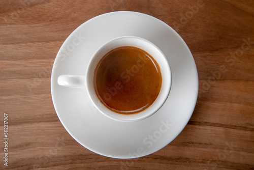 White cup of espresso on wooden background, top view	