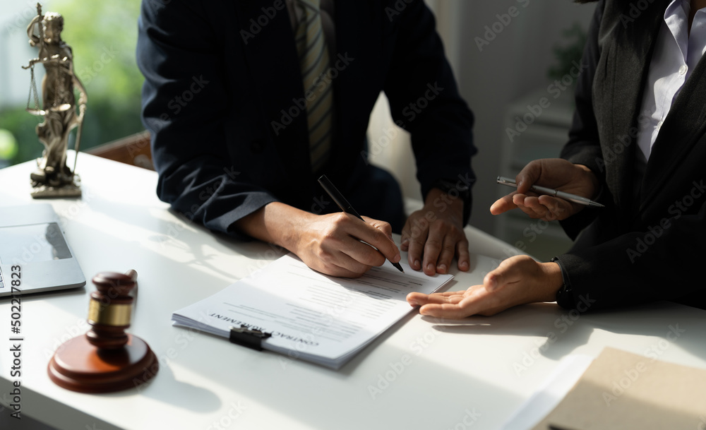 © Natee Meepian - Legal counsel presents to the client a signed contract with gavel and legal law. justice and lawyer concept.