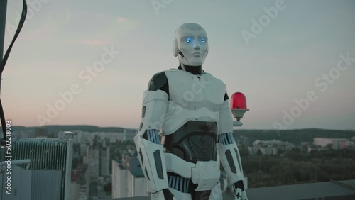AI cybernetic robot standing on rooftop building, observing modern city landscape and contemplating future plans. Automated cyborg. Innovative technology. photo