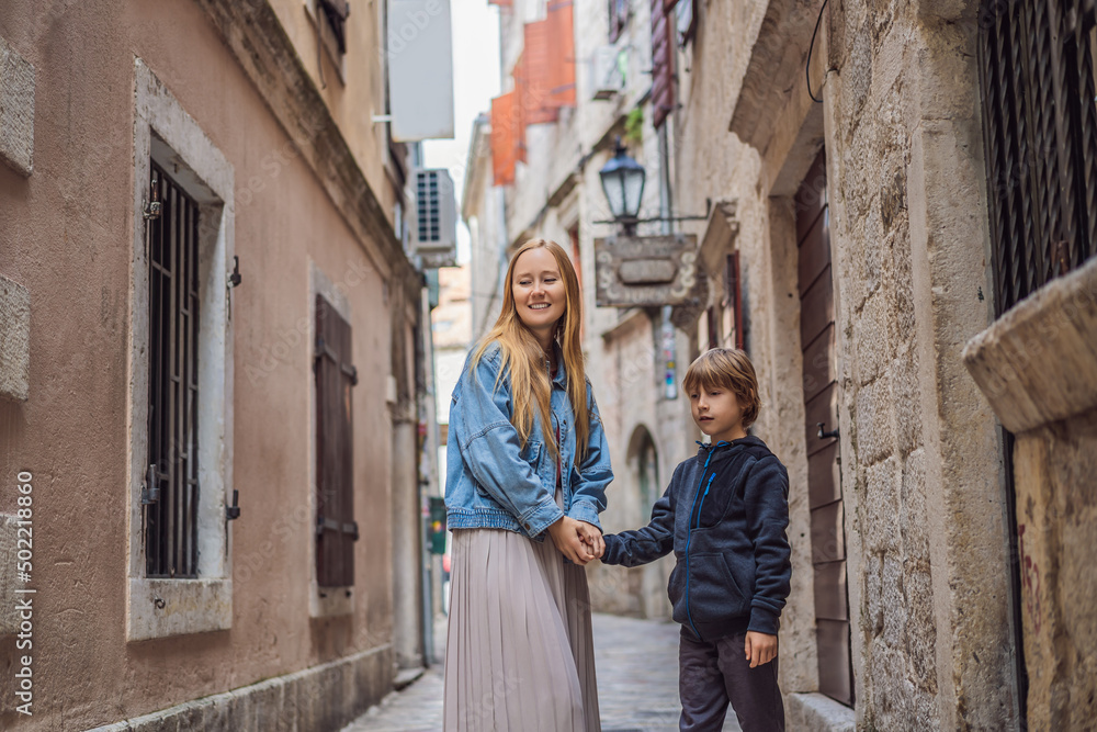 Mom and son travelers enjoying Colorful street in Old town of Kotor on a sunny day, Montenegro. Travel to Montenegro concept