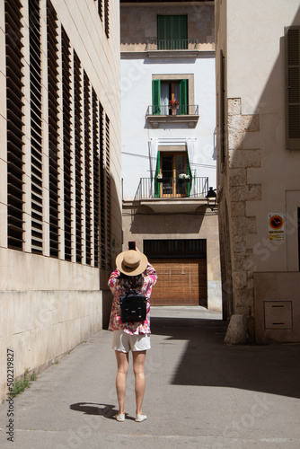 Young woman traveler with her straw hat taking pictures of the architecture of the houses on the balearic island of Palma de Mallorca, Spain © paulomachado_9