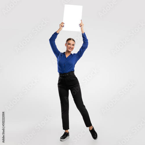 Businesswoman holding blank white advertising billboard at studio