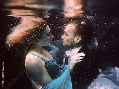 beautiful couple dancing underwater in the swimming pool