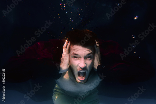 An underwater shot of a man screaming in a swimming pool on black background
