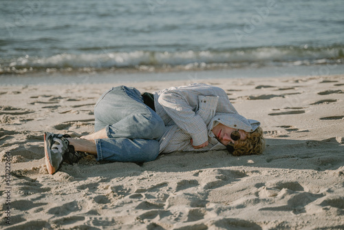 homeless man lies on the sand, hid from the cold