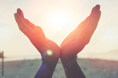 Silhouette of female hands holding sunset or sunrise for people energy and serene hope religion concept